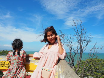 Happy woman with arms raised against sky