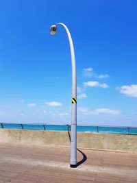 Street light on beach against blue sky
