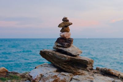 Stack of rocks in sea against sky