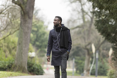 Young man looking away against trees