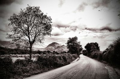 Road passing through landscape against cloudy sky