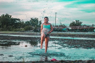 Full length of man jumping on water against sky