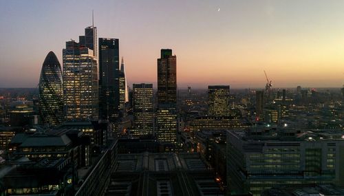 Illuminated cityscape against sky during sunset