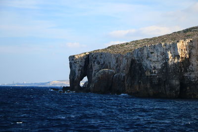 Rock formations by sea against sky