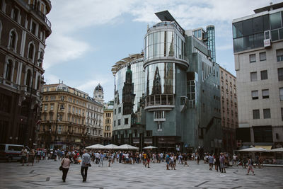 Group of people walking on street against buildings