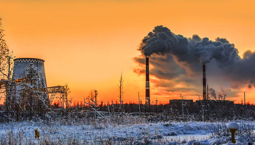 Smoke emitting from factory against sky during winter