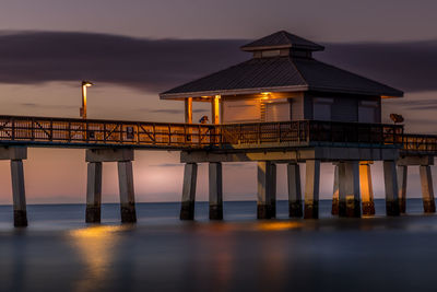 Built structure on pier against sky at sunset