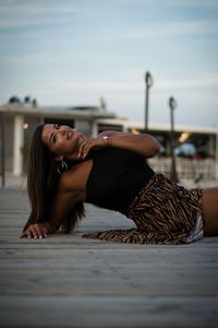 Portrait of young woman lying down against sky