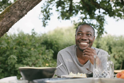 Smiling mid adult man looking away having lunch at table during garden party