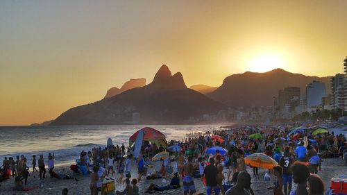 People at beach against sky during sunset