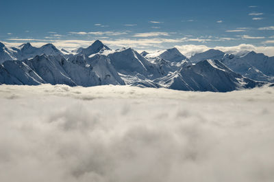 Scenic view of cloudscape by snow covered mountains against sky