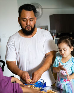 Family making kek batik or malaysian triple chocolate dessert. crushing the cookies into tiny pieces