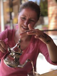 A girlpouring mint tea in a glass of tea in marrakesh, marocco. hand lifts lid of teapoat.
