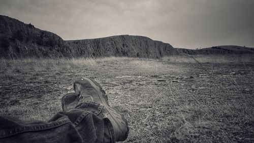 Low section of man standing on mountain against sky