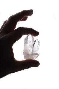 Close-up of hand holding ice over white background