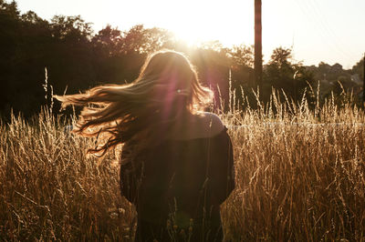 Rear view of woman standing on field against sky