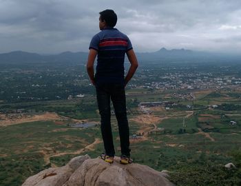 Rear view of man standing on landscape against sky