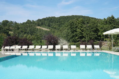 Swimming pool by trees against sky