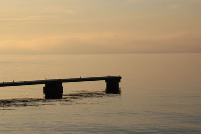 Pier over sea against sky during sunset