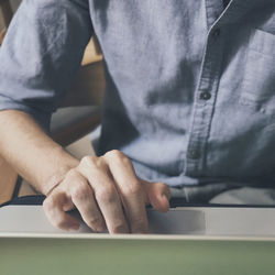 Close-up of man using mobile phone while sitting on table