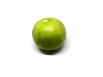 Close-up of green fruit against white background