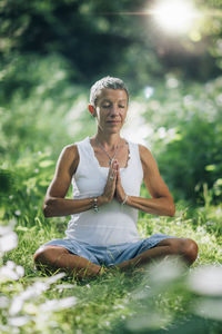 Meditation in nature. mindful woman meditating, sitting on the ground with hands in a prayer 