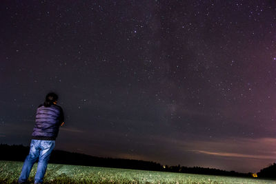Rear view of woman standing against star field at night