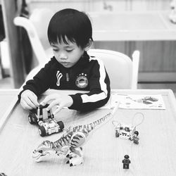 Cute boy playing with toy car on table at home