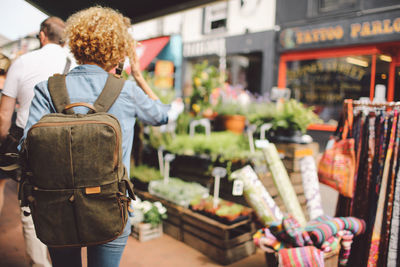 Rear view of woman walking through street market stalls in city