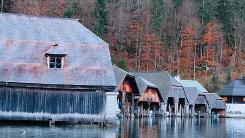 Houses by lake against buildings