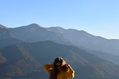 Woman standing in mountains against clear sky