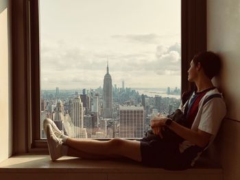 Side view of man looking at city buildings against sky