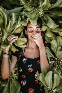Portrait of smiling woman in sunglasses standing against tree