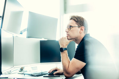 Side view of young woman using laptop while sitting at office