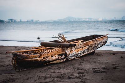 Abandoned boat on beach against sky