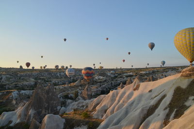 Hot air balloons flying over rocks against clear sky