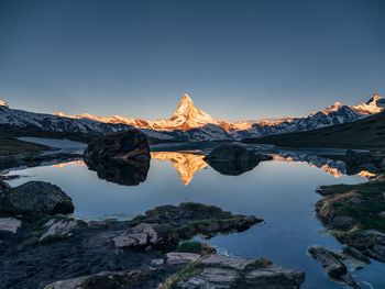 Reflection of matterhorn mountain in lake against clear sky during sunset
