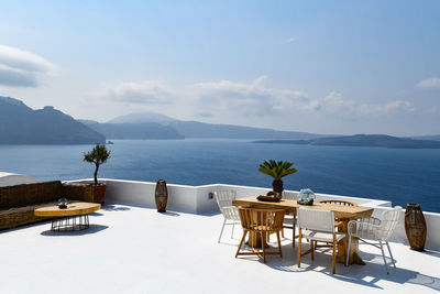 Chairs and tables by swimming pool against sky