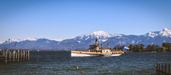 Scenic view of lake and snowcapped mountains against clear blue sky