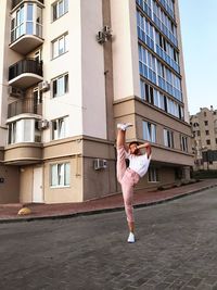 Full length of woman standing by building in city