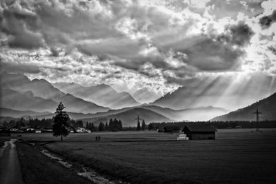 Scenic view of sunbeam through cloudy sky over landscape