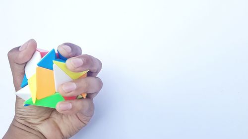 Close-up of hand holding paper over white background