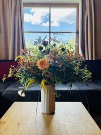 Vase with summer flowers in front of window