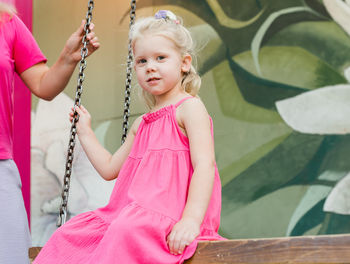 Portrait of young woman swinging at playground