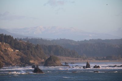 Scenic view of sea and mountains against sky