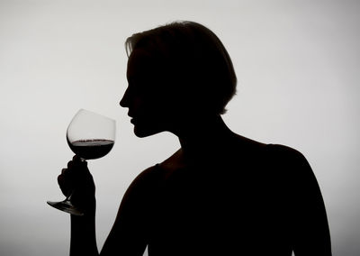 Silhouette of man drinking glass against white background