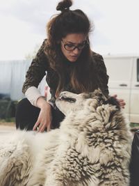 Woman with dog sitting against sky