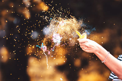 Cropped hand of woman blowing confetti