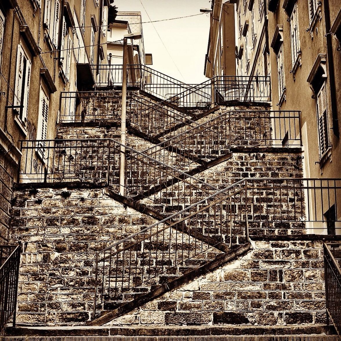 architecture, built structure, building exterior, metal, staircase, steps, railing, day, low angle view, city, building, outdoors, construction site, brick wall, no people, steps and staircases, pattern, metallic, sunlight, residential building