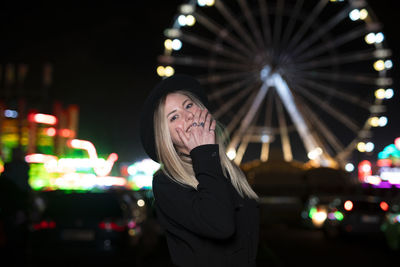 Portrait of young woman standing in city at night